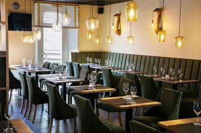 a restaurant with wooden tables and green chairs at La Couronne in Welkenraedt