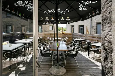 a restaurant with tables and chairs under an umbrella at La Couronne in Welkenraedt