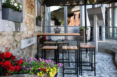 a table and chairs on a patio with flowers at La Couronne in Welkenraedt