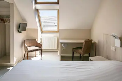 a bedroom with a bed and two chairs and a desk at La Couronne in Welkenraedt