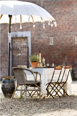 a table and chairs under an umbrella next to a building at B&B Domaine Villa Bayard in Kanne