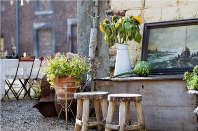 a patio with two stools and flowers and a painting at B&B Domaine Villa Bayard in Kanne