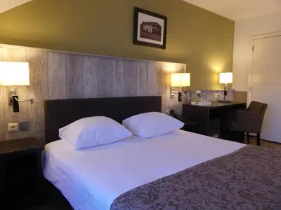 a bedroom with a bed with two pillows and a desk at Hotel De Maaskant in Maaseik
