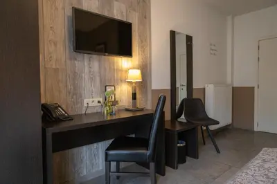 a room with a desk with two chairs and a telephone at Hotel De Maaskant in Maaseik