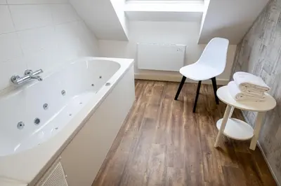 a white bathroom with a tub and a stool at Hotel De Maaskant in Maaseik