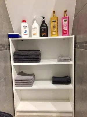 a bathroom shelf with towels and bottles of soap at Rentalis Flat in Liège