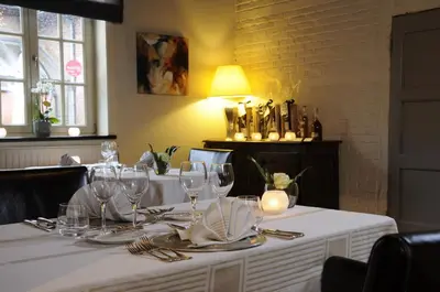 a table with a white table cloth and wine glasses at twee broeders in Riemst