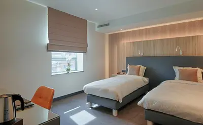 a bedroom with two beds and a desk and a window at twee broeders in Riemst
