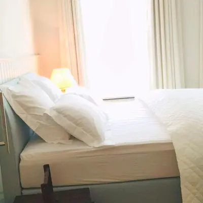 a bed with white sheets and pillows next to a window at Kirisavan Bed&Breakfast in Borgloon
