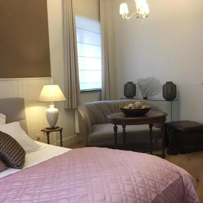 a bedroom with a bed and a couch and a table at Kirisavan Bed&Breakfast in Borgloon