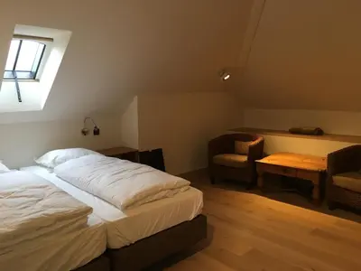 a bedroom with a bed and a chair and a window at Orshof in Oudsbergen
