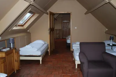 a attic room with two beds and a couch at Orshof in Oudsbergen