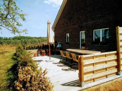 a deck with chairs and an umbrella next to a house at De Oude Katsei in Gingelom