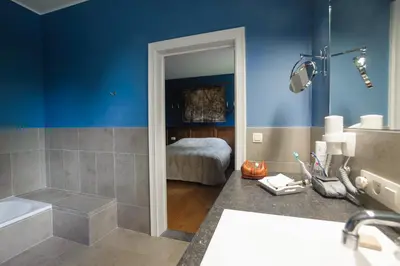 a bathroom with a tub and a bedroom with a bed at B&B Kamerijck in Gingelom
