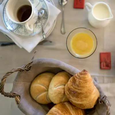 a basket of croissants and a cup of coffee on a table at B&B Kamerijck in Gingelom