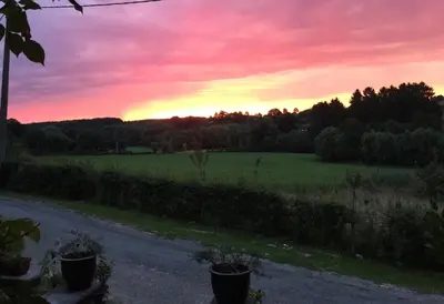 a sunset over a field with a road and trees at fermette in Lontzen