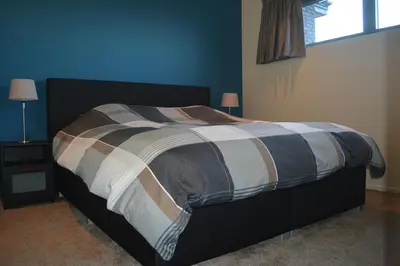 a bed in a bedroom with a blue wall at Appartroom Hasselt in Hasselt