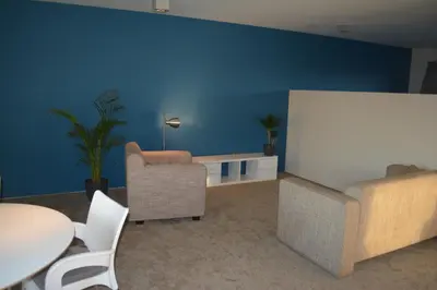 a living room with blue walls and chairs and a whiteboard at Appartroom Hasselt in Hasselt
