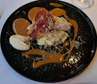 a black plate of food on a table at Hotel Restaurant De Kommel in Voeren