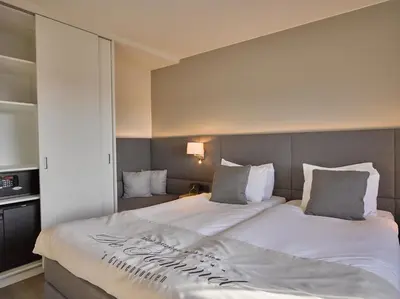 a bedroom with a large white bed with aigil at Hotel Restaurant De Kommel in Voeren