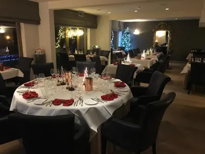 a dining room with white tables and chairs and a christmas tree at Hotel Restaurant De Kommel in Voeren