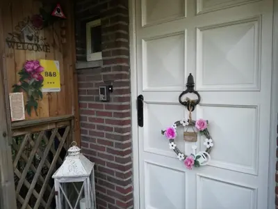 a door with a wreath on it next to a brick wall at La Rose in Overpelt