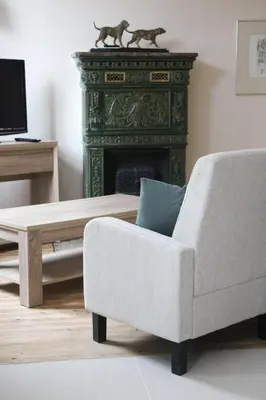 a living room with a chair and a fireplace at De Koetsier in Lanaken