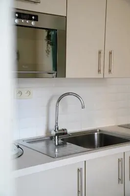 a kitchen with a sink and a microwave at De Koetsier in Lanaken
