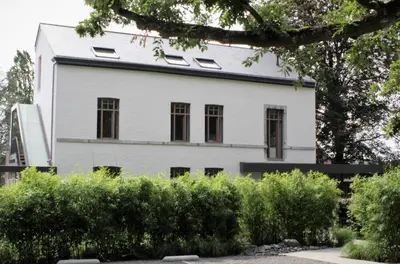 a white house with black windows and bushes at Les Begards Espace 9 in Chaudfontaine