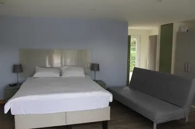 a bedroom with a large bed and a bench at Logie Rotem in Dilsen-Stokkem
