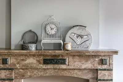 a stone fireplace with a clock on top of it at Villa Copis in Borgloon