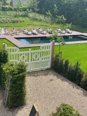 a white fence with chairs and a pool in a yard at Villa Copis in Borgloon