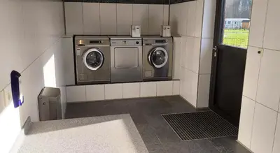 a laundry room with two washing machines and a window at Vakantiepark Wilhelm Tell Vakantieappartement in Oudsbergen