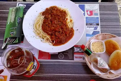 a table with a plate of spaghetti and a bowl of bread at Vakantiepark Wilhelm Tell Vakantieappartement in Oudsbergen