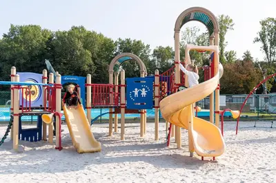 a child and a dog playing on a playground at Vakantiepark Wilhelm Tell Vakantieappartement in Oudsbergen