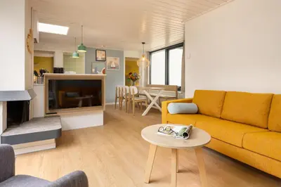 a living room with a yellow couch and a table at Center Parcs Vossemeren in Lommel