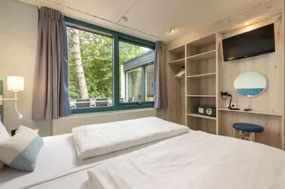 a bedroom with a large white bed with a window at Center Parcs Vossemeren in Lommel