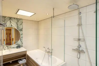 a bathroom with a shower and a tub and a sink at Center Parcs Vossemeren in Lommel