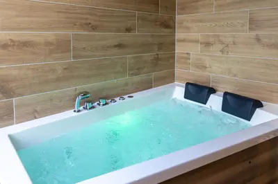 a bath tub with two black chairs in a bathroom at Center Parcs Vossemeren in Lommel