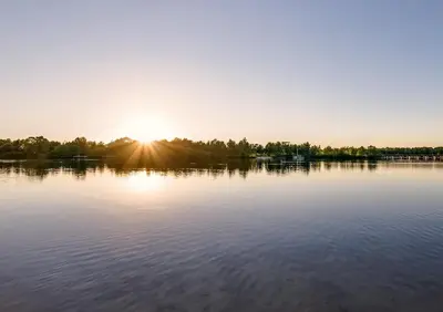 a view of a lake with the sun setting at Center Parcs Vossemeren in Lommel