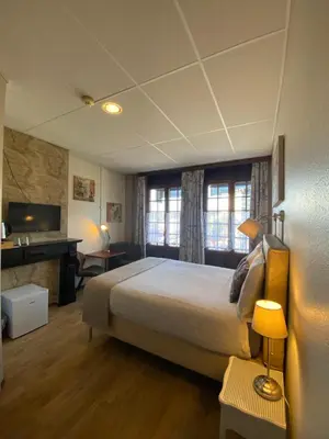 a bedroom with a bed and a desk and a television at Hotel Des Ardennes in Verviers
