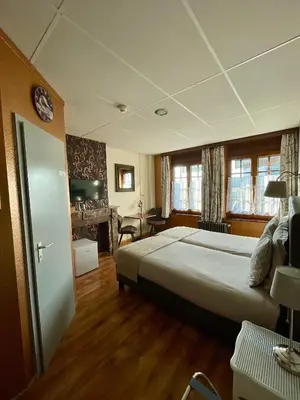 a bedroom with a large bed and a fireplace at Hotel Des Ardennes in Verviers