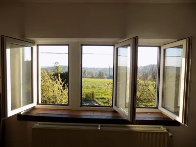 a room with three windows with a view of a field at (La parenthese) in Hombourg
