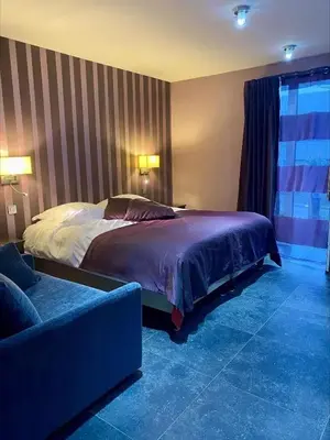 a bedroom with a large bed and a couch at Hotel L'Ami du Chambertin in Thimister
