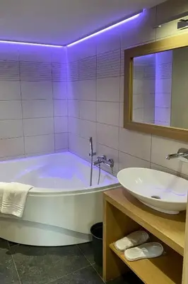 a bathroom with a tub and a sink at Hotel L'Ami du Chambertin in Thimister