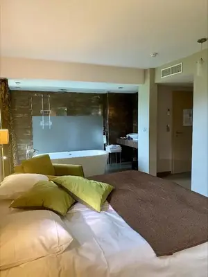 a bedroom with a large bed and a bath room at Hotel L'Ami du Chambertin in Thimister