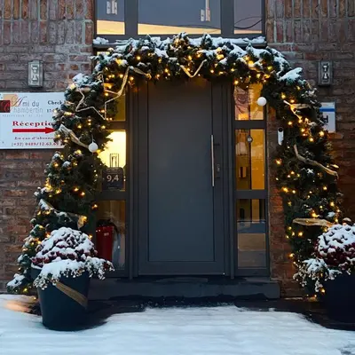 a door with a christmas wreath and a christmas tree at Hotel L'Ami du Chambertin in Thimister