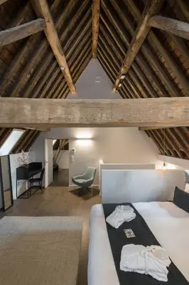 a attic bedroom with a bed and a chair at Martin's Rentmeesterij in Bilzen