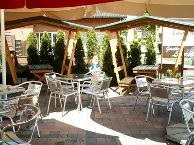a patio with tables and chairs under an umbrella at gasthof lederhose in Diepenbeek