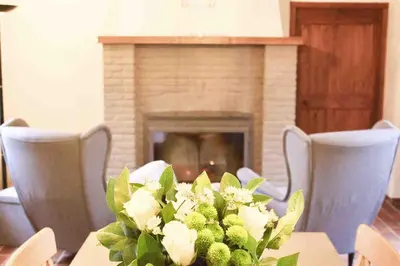 a table with a vase of flowers and a fireplace at De Hoog Weyen in Halen